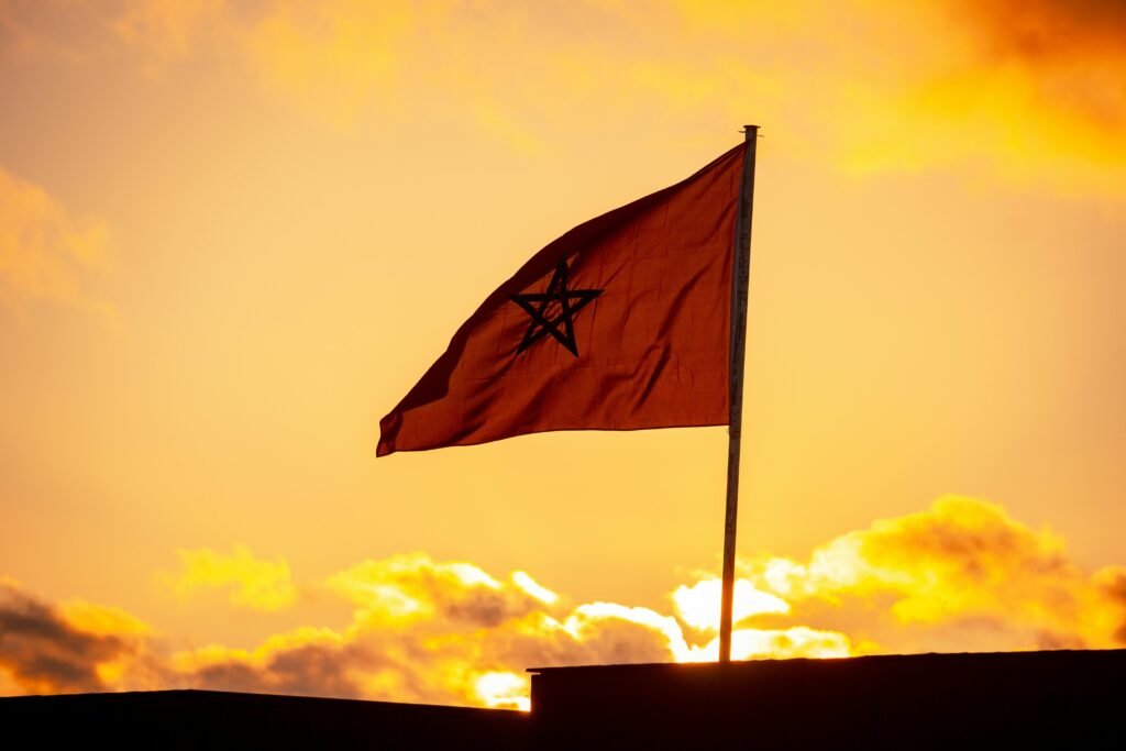 Beautiful silhouette of Moroccan flag against vibrant sunset sky in Sidi Rahal, Morocco.
